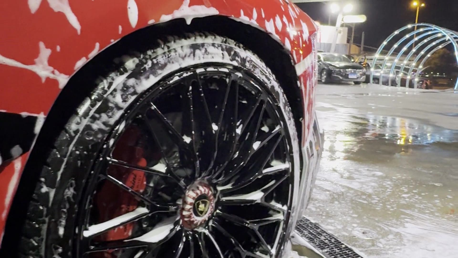 Red Lamborghini Aventador SV covered in foam at Magic Wash at night